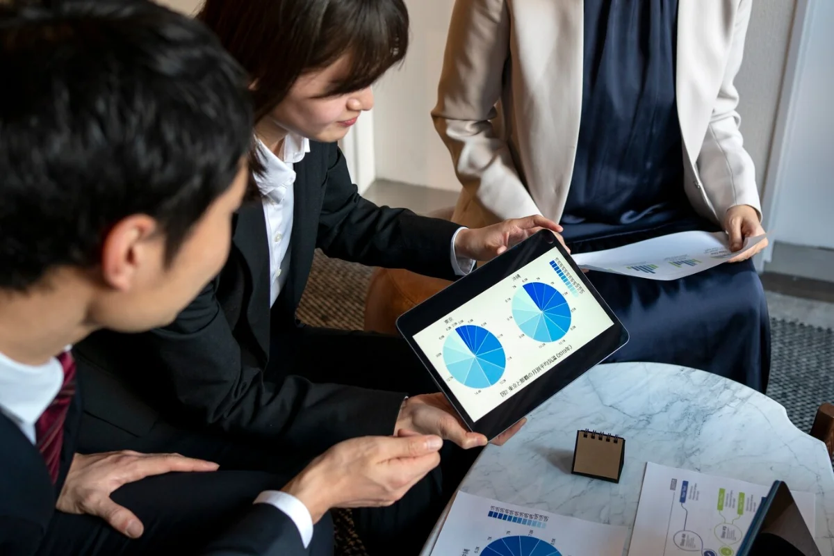Three professionals examining data charts on a tablet during a business meeting.