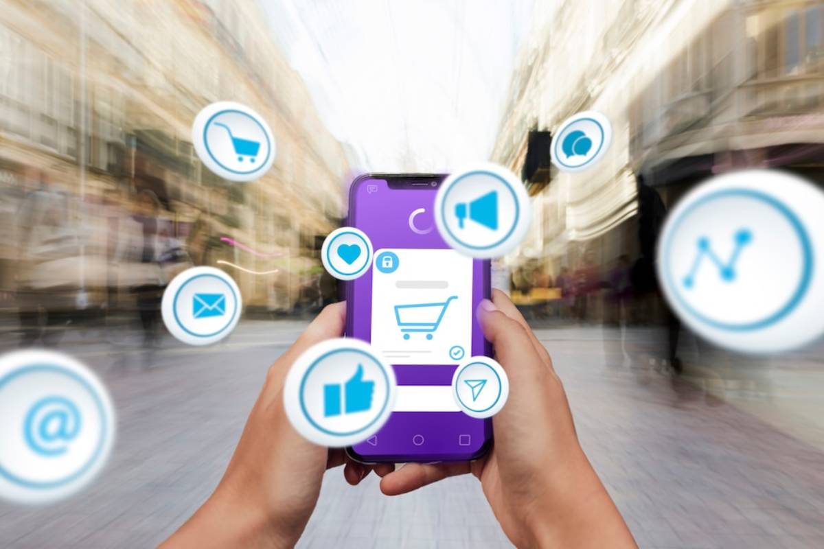 Hands holding smartphone displaying various app icons on blurred city street background.