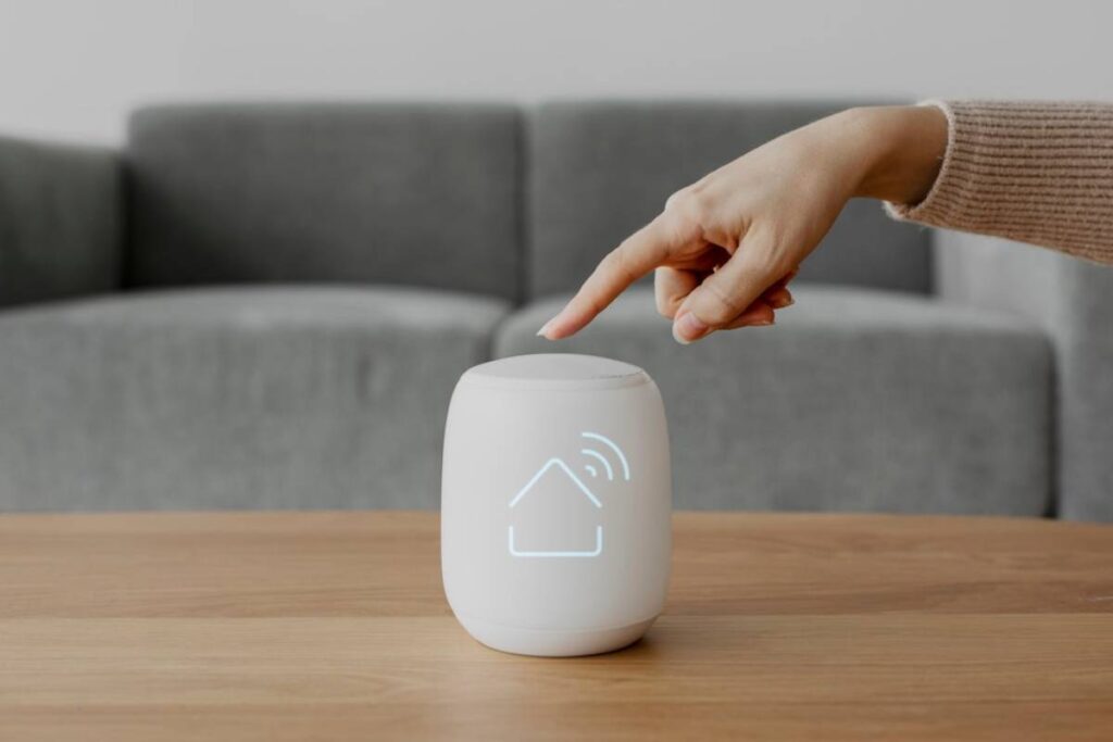 A person's hand interacting with a smart home device on a wooden table.