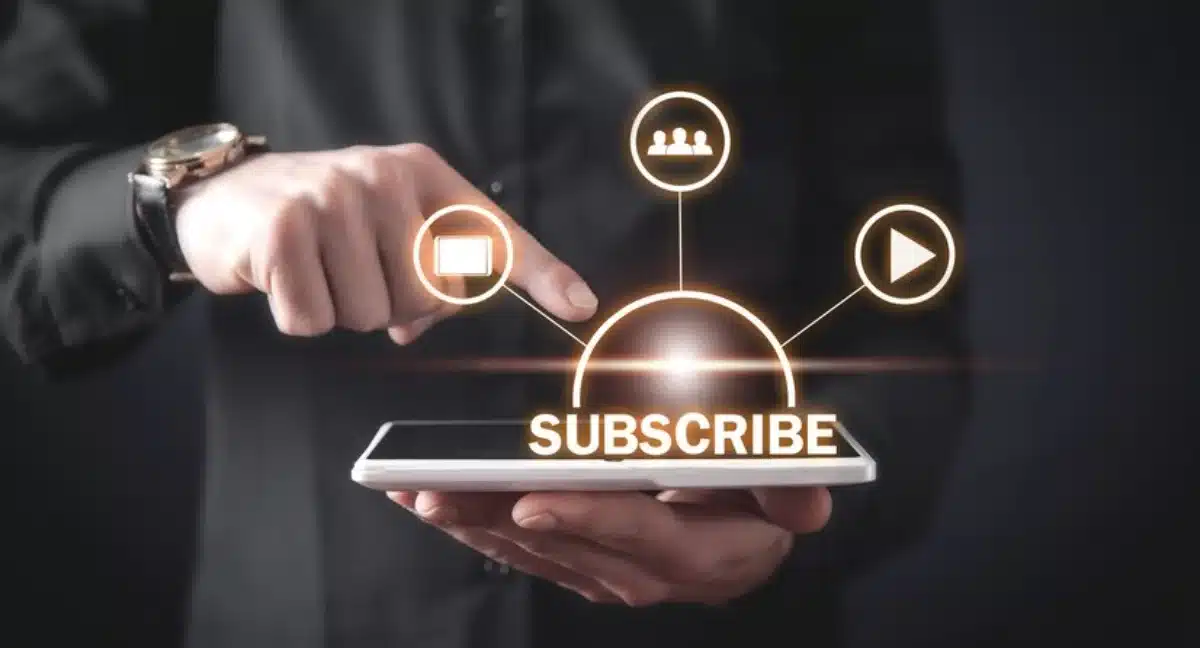 Person holding a smartphone displaying a floating, interactive Subscribe button with related social media icons.