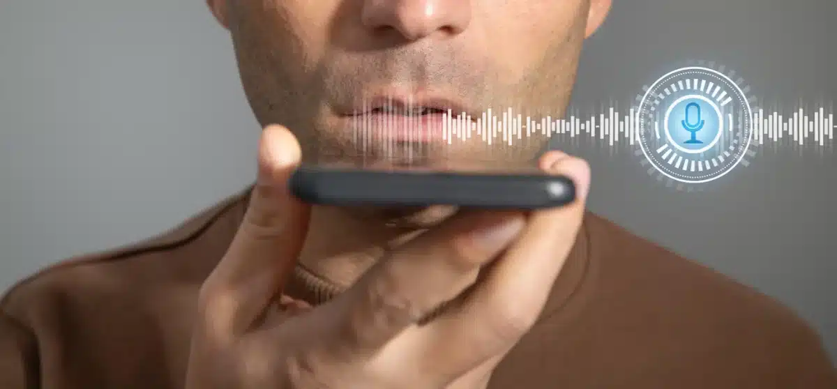 Man using voice command on his smartphone, with a graphical soundwave and microphone icon overlay.