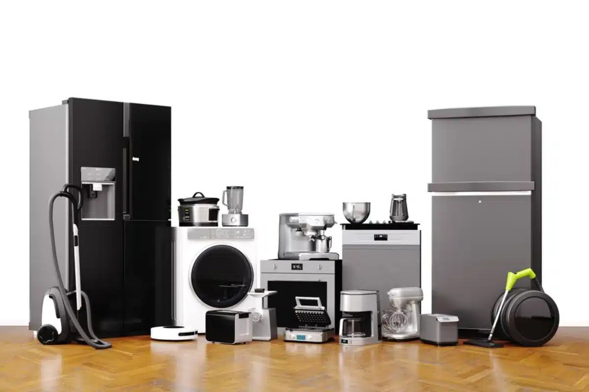 An assortment of modern household appliances, including a refrigerator, washing machine, and small kitchen devices, displayed on a wooden floor.