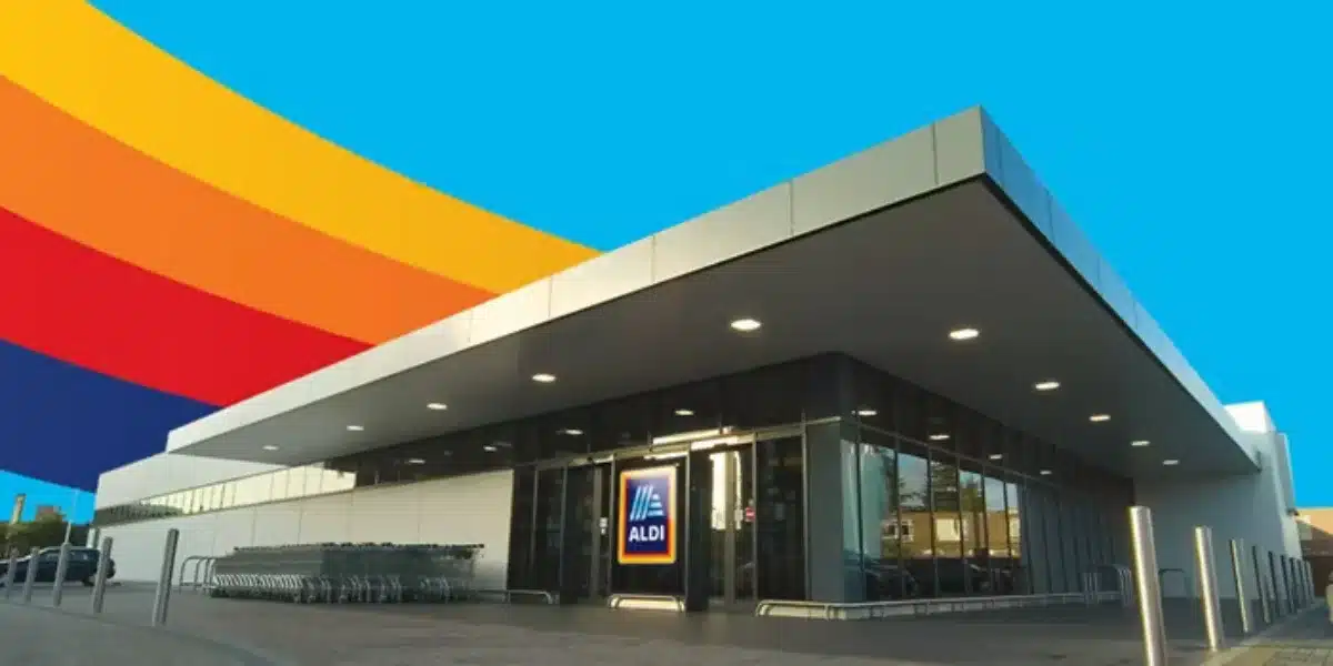 Modern Aldi supermarket exterior with bold, colourful stripes overhead and visible shopping carts.